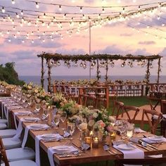 an outdoor dining area with tables and chairs set up for a wedding reception at dusk