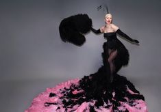 a woman in a black and pink dress with feathers on her head is posing for the camera