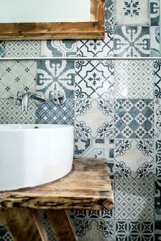 a white sink sitting on top of a wooden table in front of a tiled wall