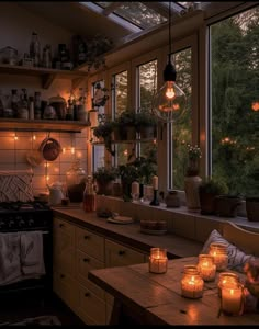 candles are lit on the kitchen counter in front of an open window with lots of greenery