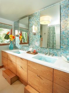 a bathroom with two sinks, mirrors and blue tiles on the backsplashes