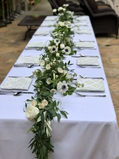 a long table with white flowers and place settings