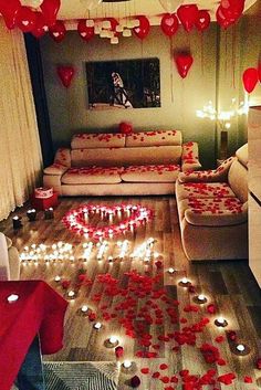 a living room filled with lots of red hearts floating in the air and candles on the floor