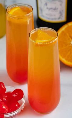 two glasses filled with liquid next to orange slices