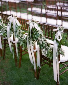 the wedding ceremony was decorated with greenery and white ribbon tied around the back of chairs