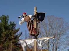 a pirate ship statue on top of a pole with trees in the backgroud