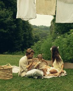 a man and two women sitting on the grass with a baby in front of them