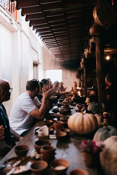 several people sitting at a long table with bowls and cups on it, all clapping