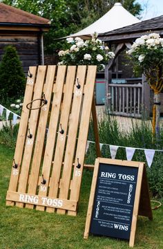 a wooden sign sitting on top of a lush green field next to a chalkboard