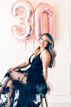 a woman sitting on a chair in front of a balloon and the number 30 sign