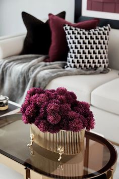 a living room with a couch, coffee table and flower arrangement on the glass top