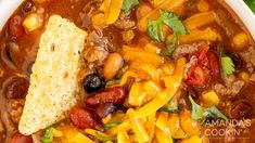 a close up of a bowl of chili and bean soup with bread on the side