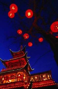 red lanterns are lit up in the night sky above a chinese building and pagoda tower