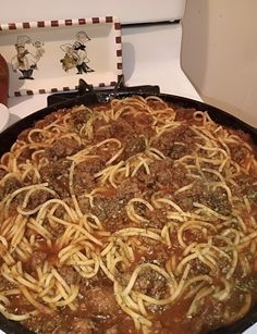 a pan filled with spaghetti and meat on top of a stove