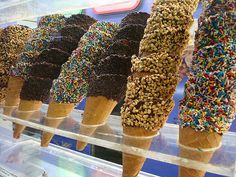 ice cream cones with sprinkles and birdseed are lined up in a display case