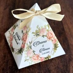 an origami box with flowers on it and a ribbon tied around the top