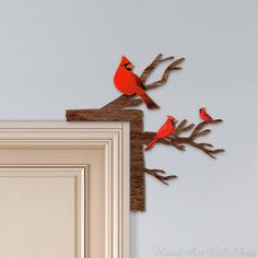 two red birds are perched on the branches of a tree and one is sitting on top of another branch