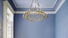 a chandelier hanging from the ceiling in a room with blue walls and white trim