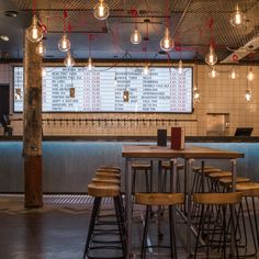 an empty restaurant with lots of stools and tables in front of a large screen