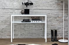 a white table with some books on it next to a lamp and two black boots