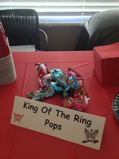 a red table topped with candy and a sign that says king of the ring pops