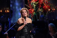 a woman in a black dress holding a microphone