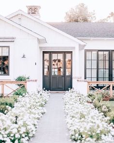 a house with white flowers in front of it and a black door on the side