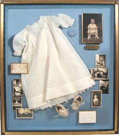 a display case with pictures and baby clothes on it