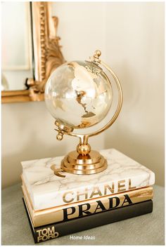 a marble globe on top of a book in front of a gold framed wall mirror