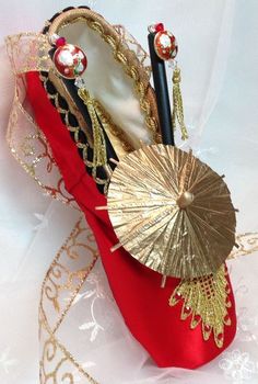 a pair of red shoes sitting on top of a white cloth covered floor next to a gold umbrella