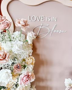 flowers are arranged in front of a sign that says love is in bloom