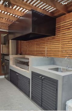 an outdoor kitchen with stainless steel appliances and wood slats on the wall behind it