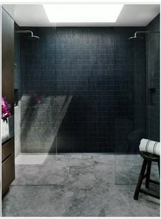 a bathroom with a walk in shower sitting next to a counter top and wooden stool