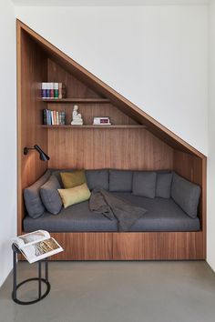 a couch sitting under a slanted wall next to a book shelf