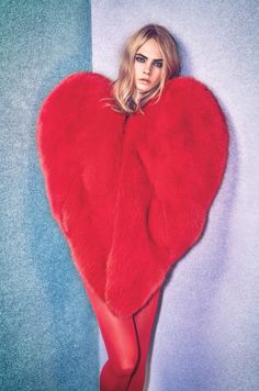 a woman in red is posing with a heart shaped fur coat