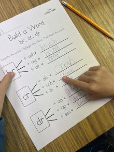 a child's hand on top of a piece of paper next to a pencil