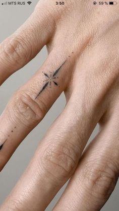 two fingers with tattoos on them, one has a cross and the other has a dragonfly