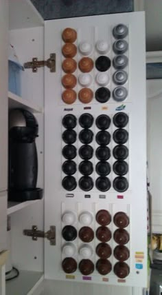 a kitchen cabinet filled with lots of donuts on top of white cupboards next to a coffee maker