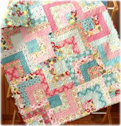 a pink and blue quilt sitting on top of a wooden chair