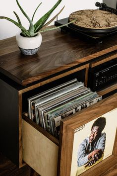 an old record player is sitting on top of a wooden cabinet with records in it