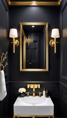 a bathroom with black walls, gold trim and a white sink in front of a mirror