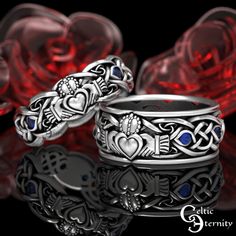 two wedding rings with blue stones in the middle and hearts on each side, surrounded by red roses