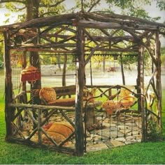 a gazebo made out of logs and wood in the grass