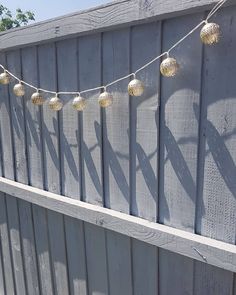 some lights are hanging on the side of a wooden fence and there is no image here to provide a caption for