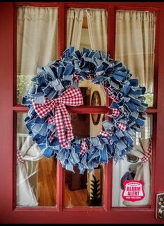 a red door with a blue and white wreath hanging on it's glass front door