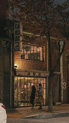 two people standing in front of a building at night