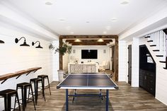 a ping pong table is in the middle of a room with bar stools