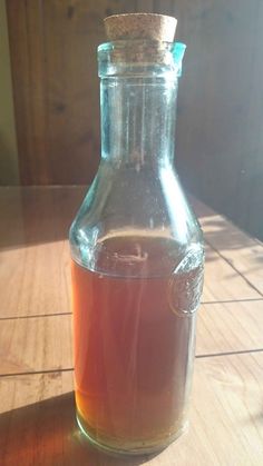 a glass bottle filled with liquid sitting on top of a wooden table