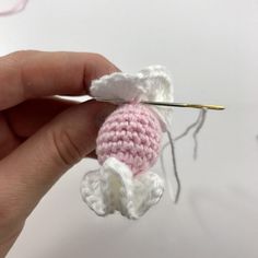 someone is crocheting a small pink and white stuffed animal with a pair of scissors