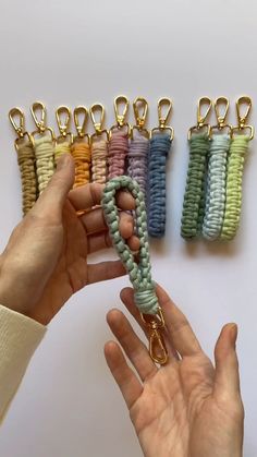 a person is holding several different colored lanyards in their hands, with one being held up by the other hand